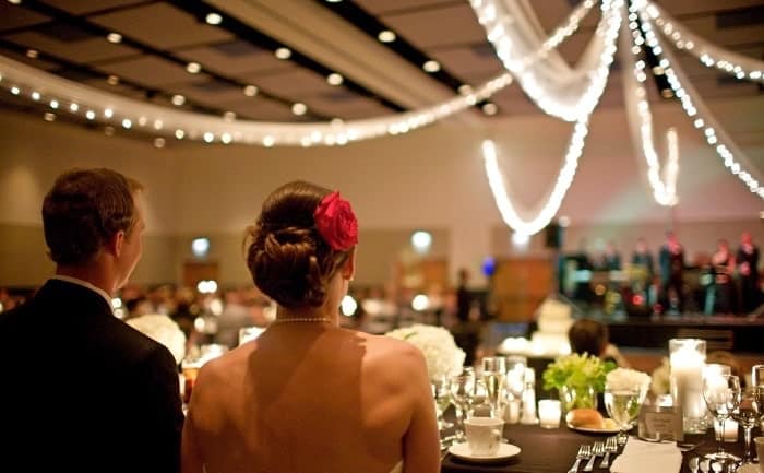 Image of Wedding Couple at the Penn Stater Hotel in front of the ballroom with their guests.